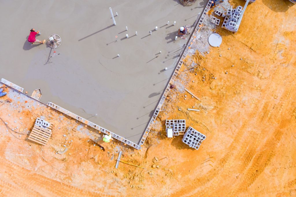 After concrete is poured on wet foundation, mason polishes concrete using concrete polishing machine.